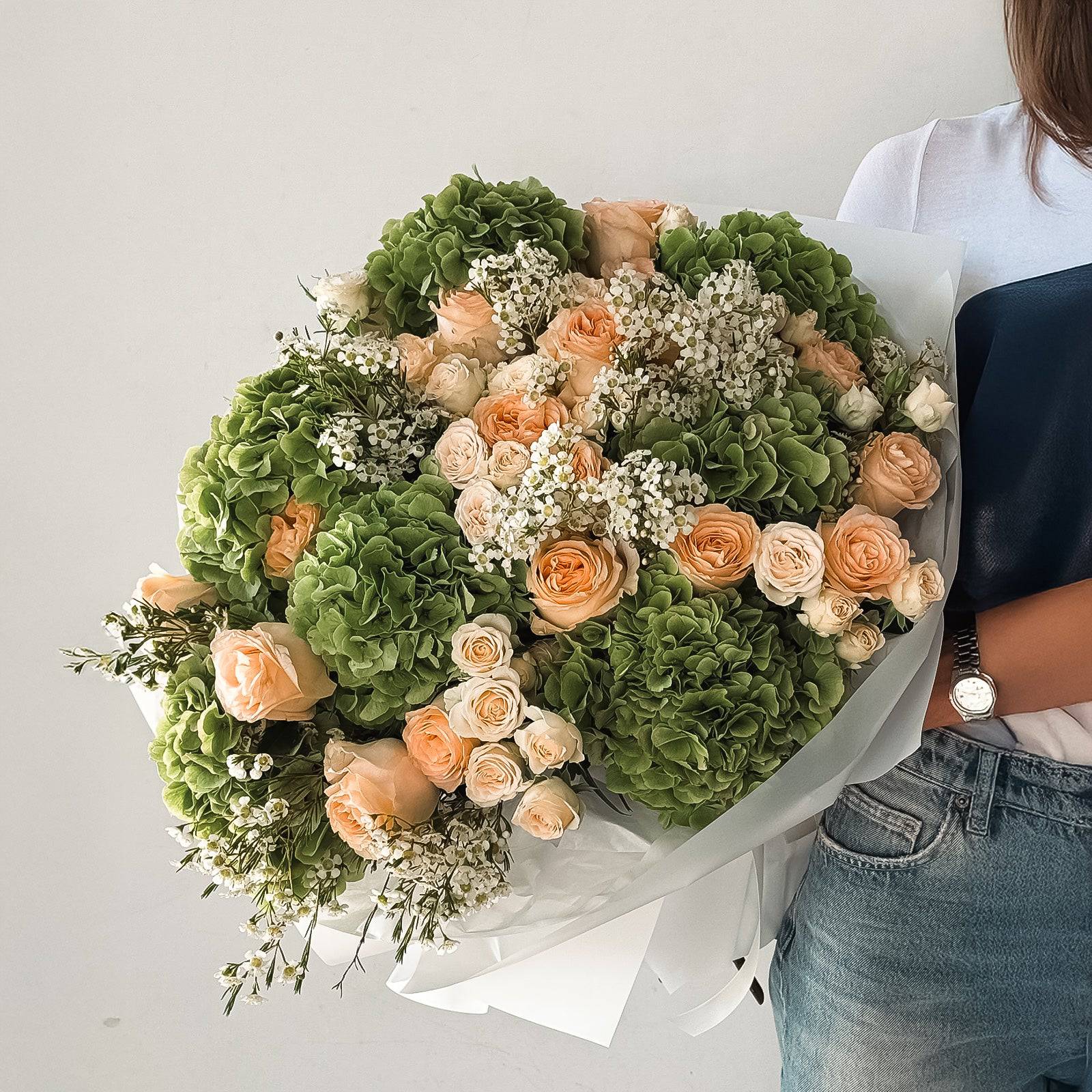 Verdant Elegance bouquet with apricot roses and green hydrangeas wrapped in white paper