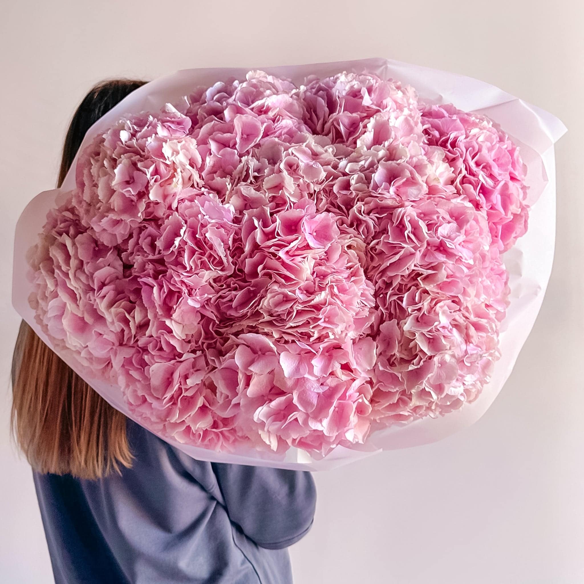 Rounded bouquet of fuchsia and soft pink hydrangeas with ruffled petals—vibrant and cheerful.