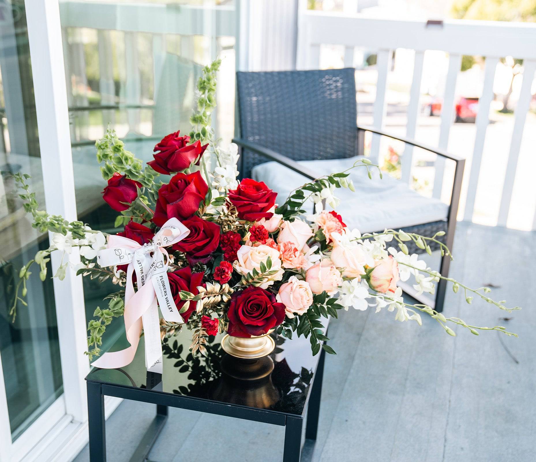 Romantic red and blush rose arrangement styled on a chair in natural light
