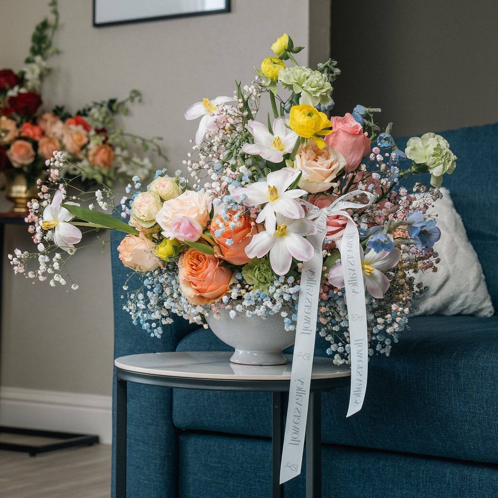 Pastel floral bouquet in vase styled on a blue chair with morning light