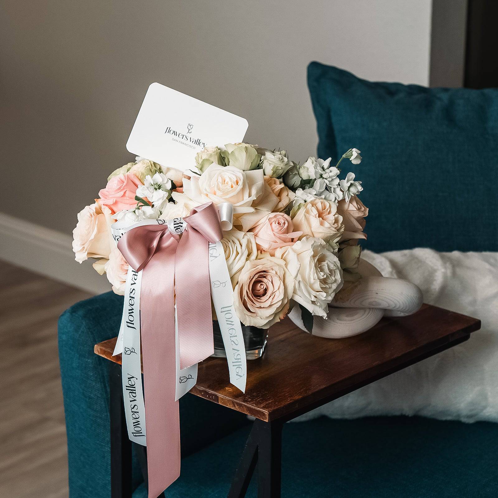 Romantic blush flower arrangement displayed on chair with satin ribbon accent