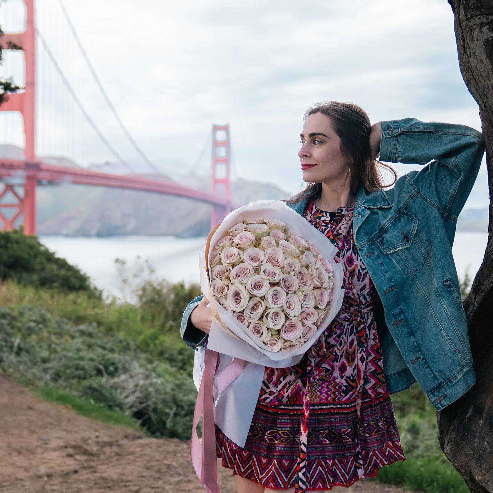 Woman holding a large Quicksand rose bouquet near Golden Gate Bridge