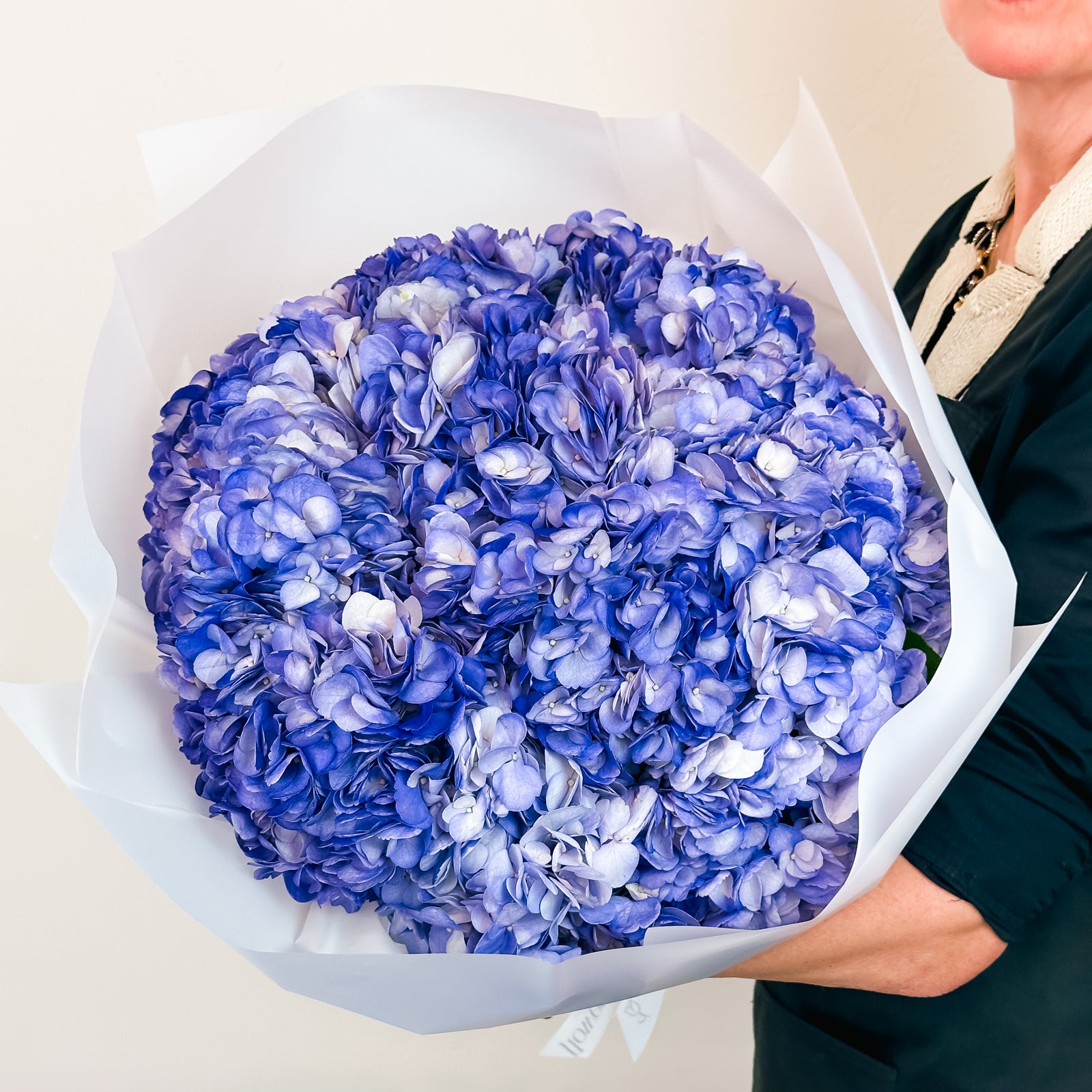 Deep violet and periwinkle hydrangeas wrapped in clean white paper—bold and refreshing floral style.