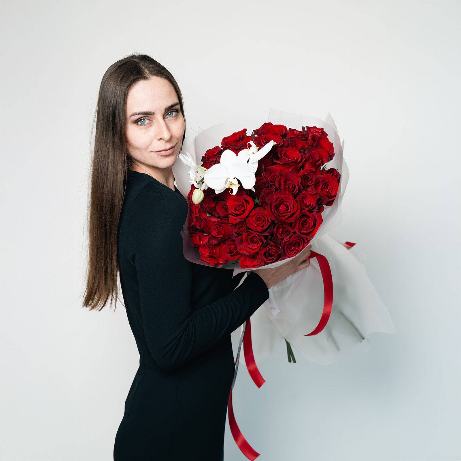 Woman holding Orchid Embrace rose and orchid bouquet wrapped for gifting