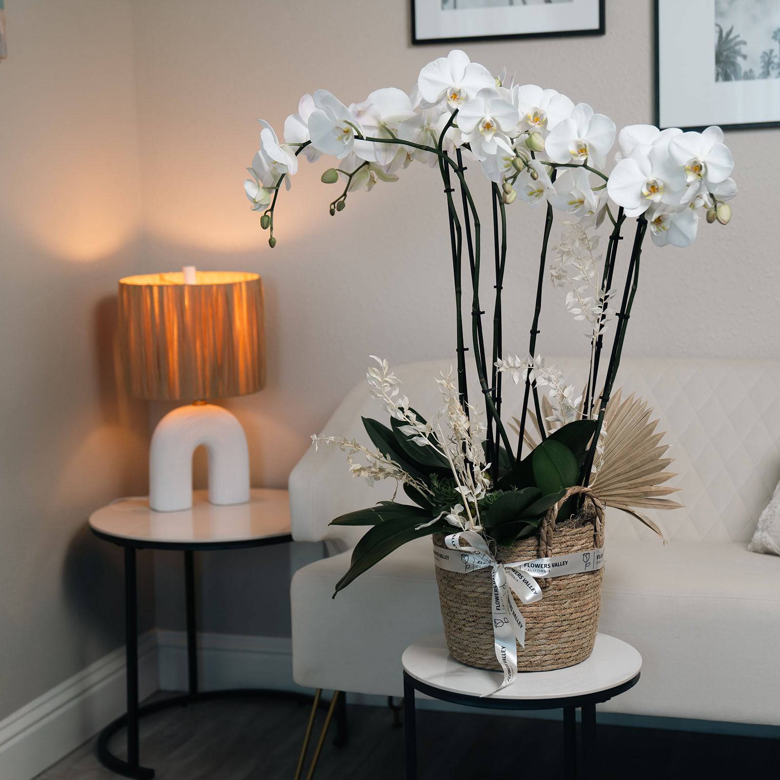 White orchid arrangement placed on a wooden side table in a serene interior.
