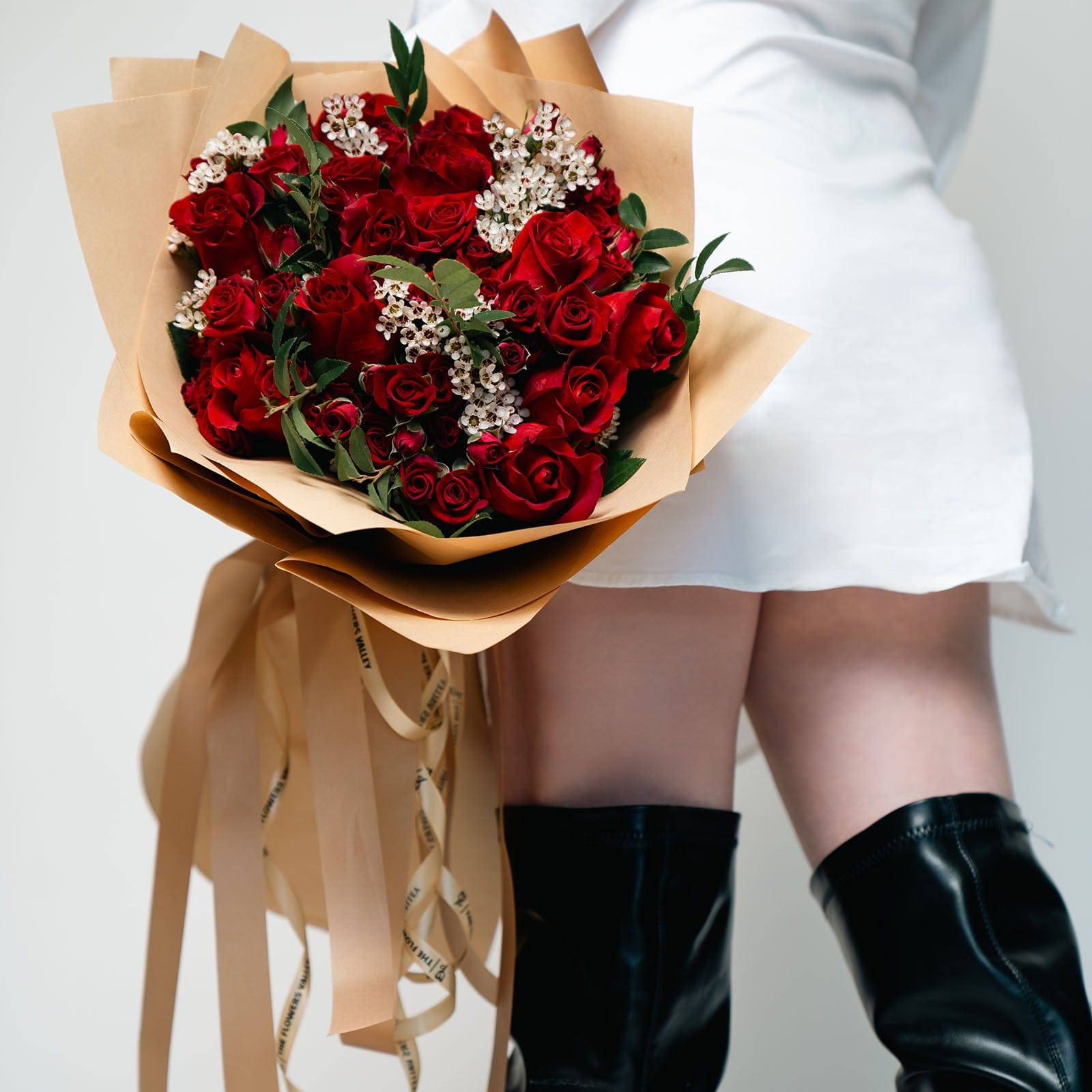 Scarlet Charm bouquet with red roses and greenery wrapped in tan paper