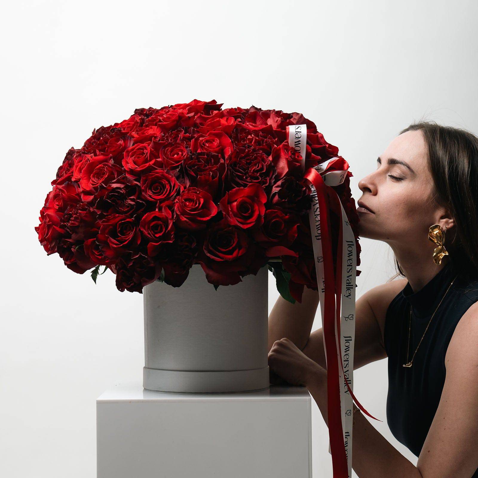 Woman leaning toward 100 red rose signature box by Flowers Valley