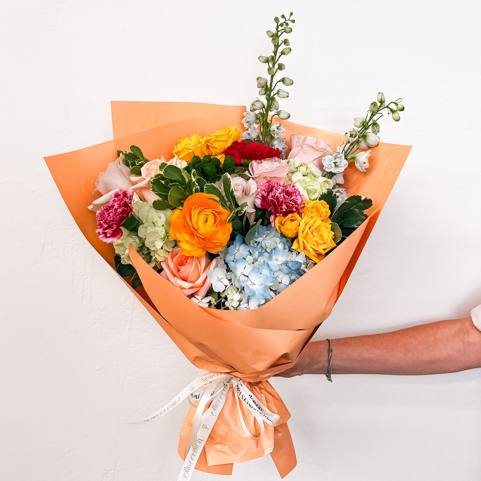 Tangerine Twist flower bouquet, a vibrant mix of blue, green, yellow, pink, and red fresh flowers wrapped in orange paper, for premium Bay Area flower delivery from The Flowers Valley.