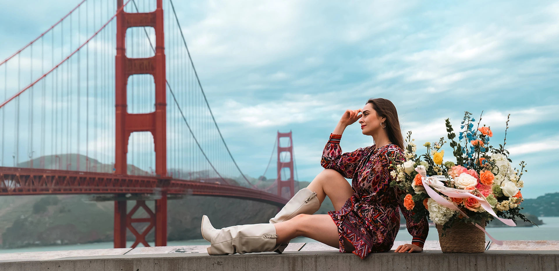 Woman with flowers overlooking Golden Gate Bridge, symbolizing flower delivery across the San Francisco Bay Area