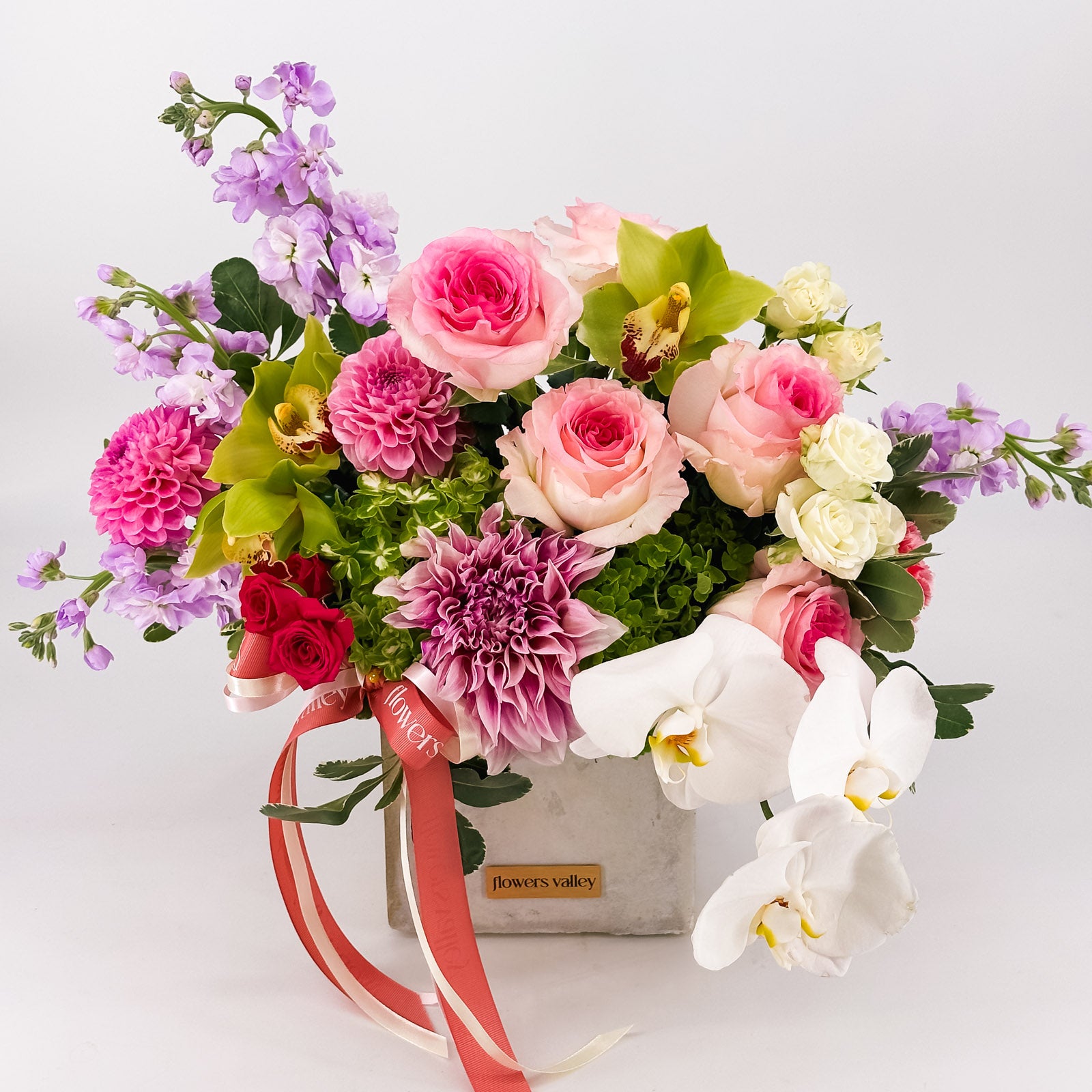 Fuchsia Garden Bloom, a vibrant pink, purple, and green floral with roses, stock, orchids, and dahlias in a concrete vase, viewed from a slightly higher angle, for premium Bay Area delivery.