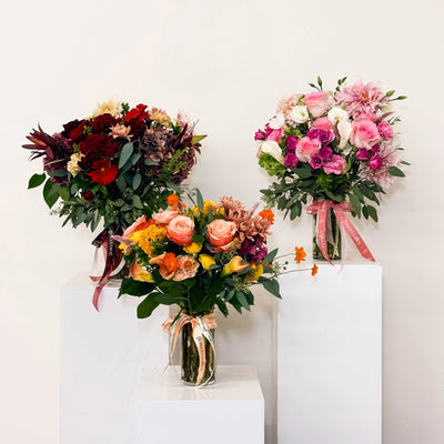 Three colorful flower bouquets on white pedestals against a light background - Haute Bloom Flower Subscription plan from Flowers Valley