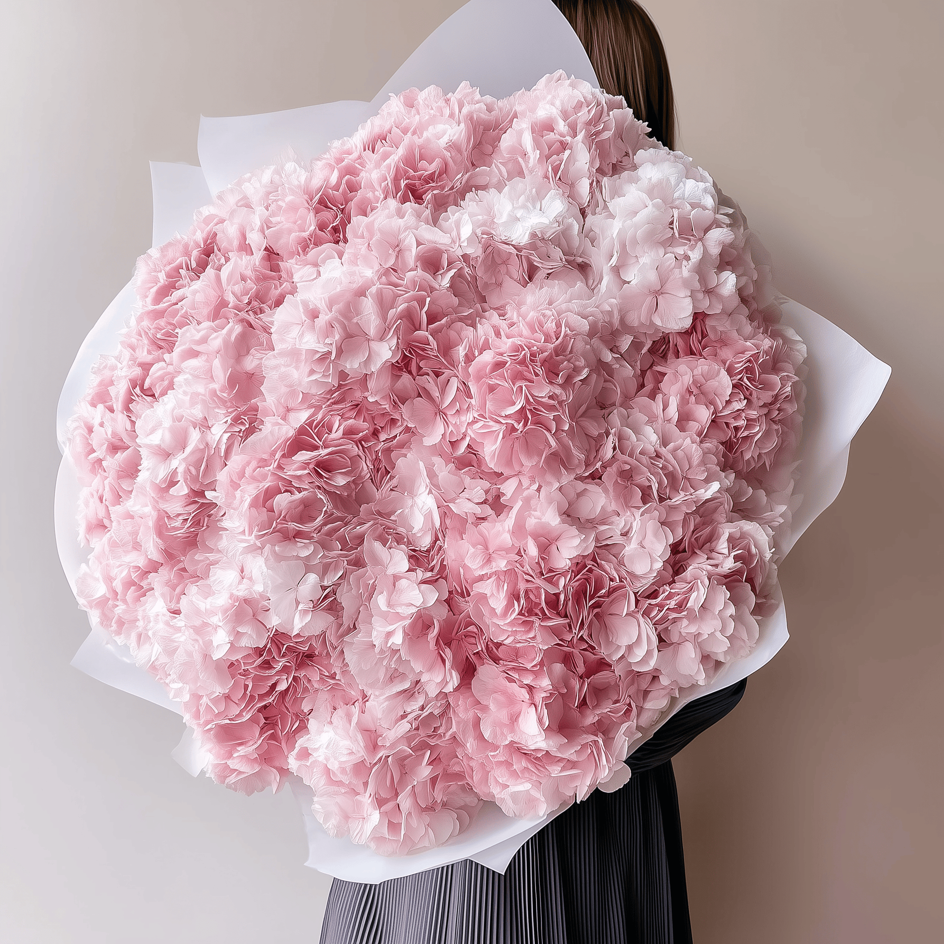 Soft pink hydrangea bouquet held by person in front of neutral background—romantic and delicate.