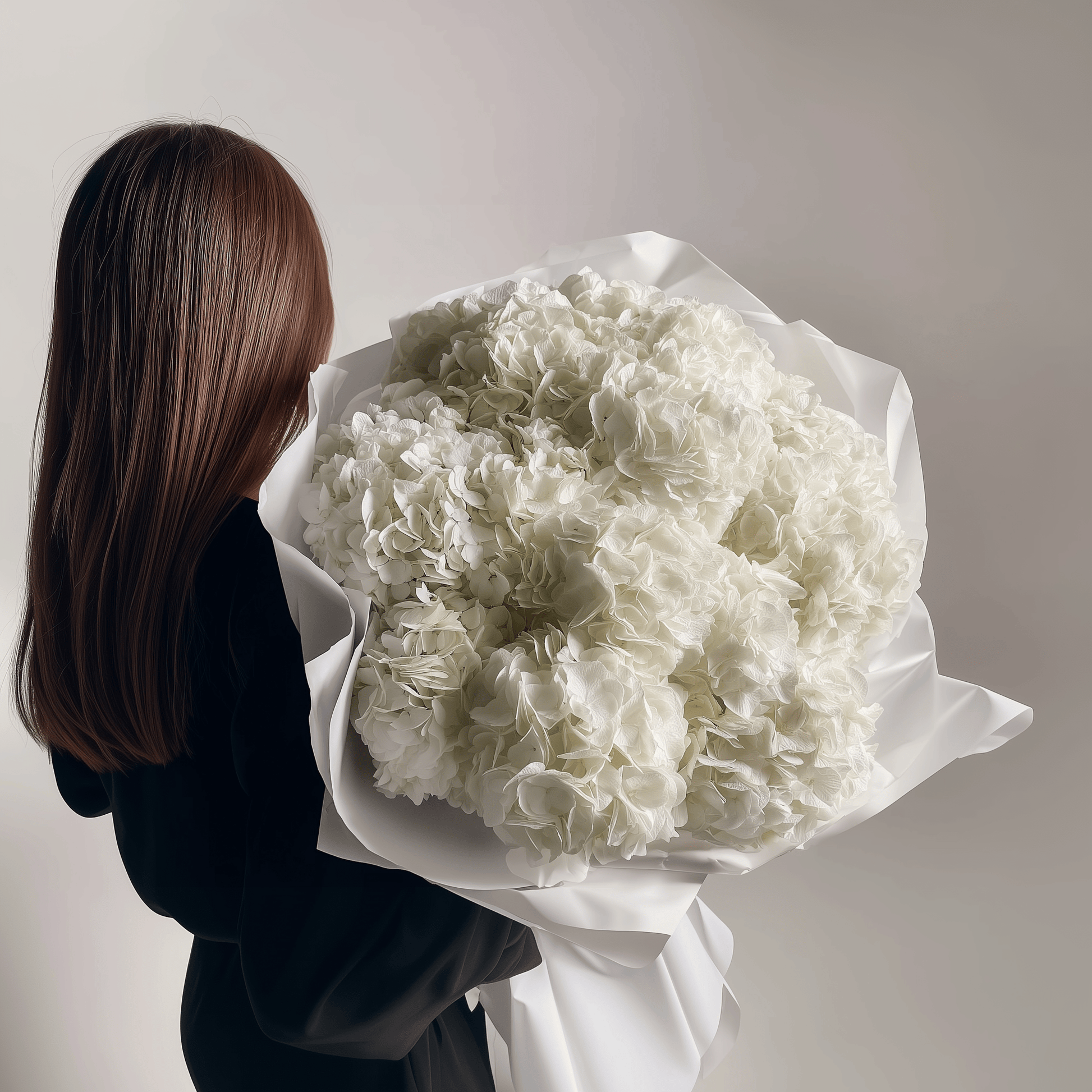 Bouquet of ivory-white hydrangeas held in both hands—clean, timeless arrangement.