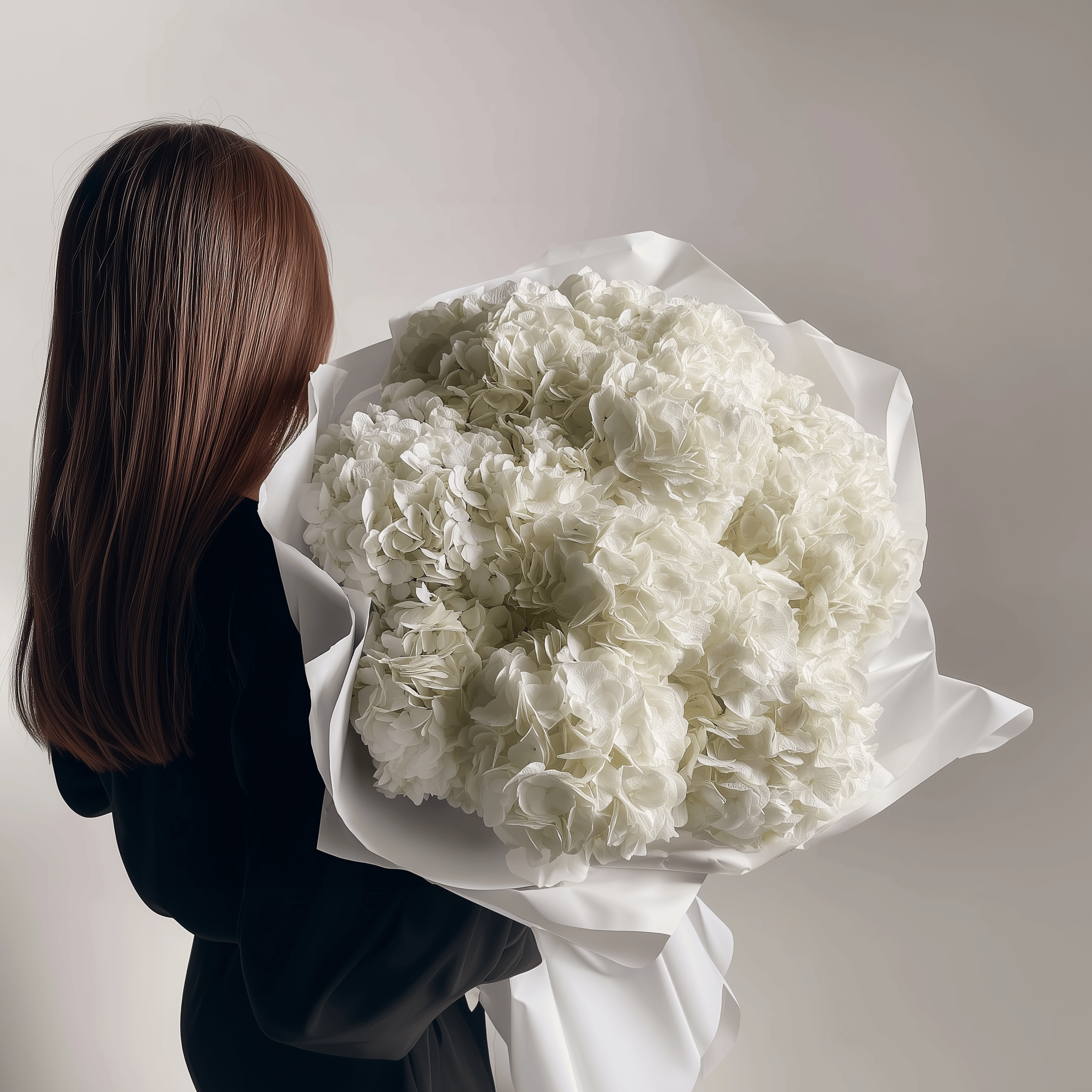 Bouquet of ivory-white hydrangeas held in both hands—clean, timeless arrangement.