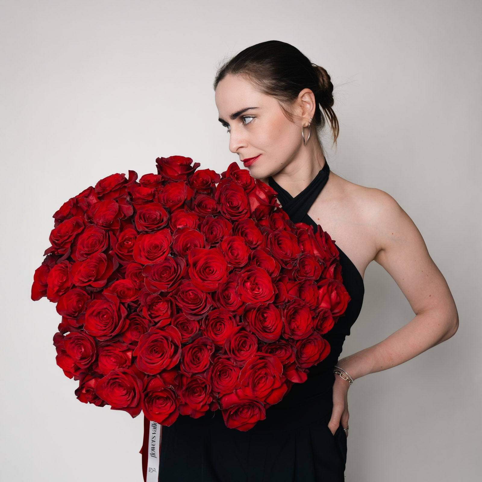 Woman holding the vibrant Long-stem Red Roses flower bouquet in front of her, showcasing the lush red blooms, available for premium Bay Area flower delivery.