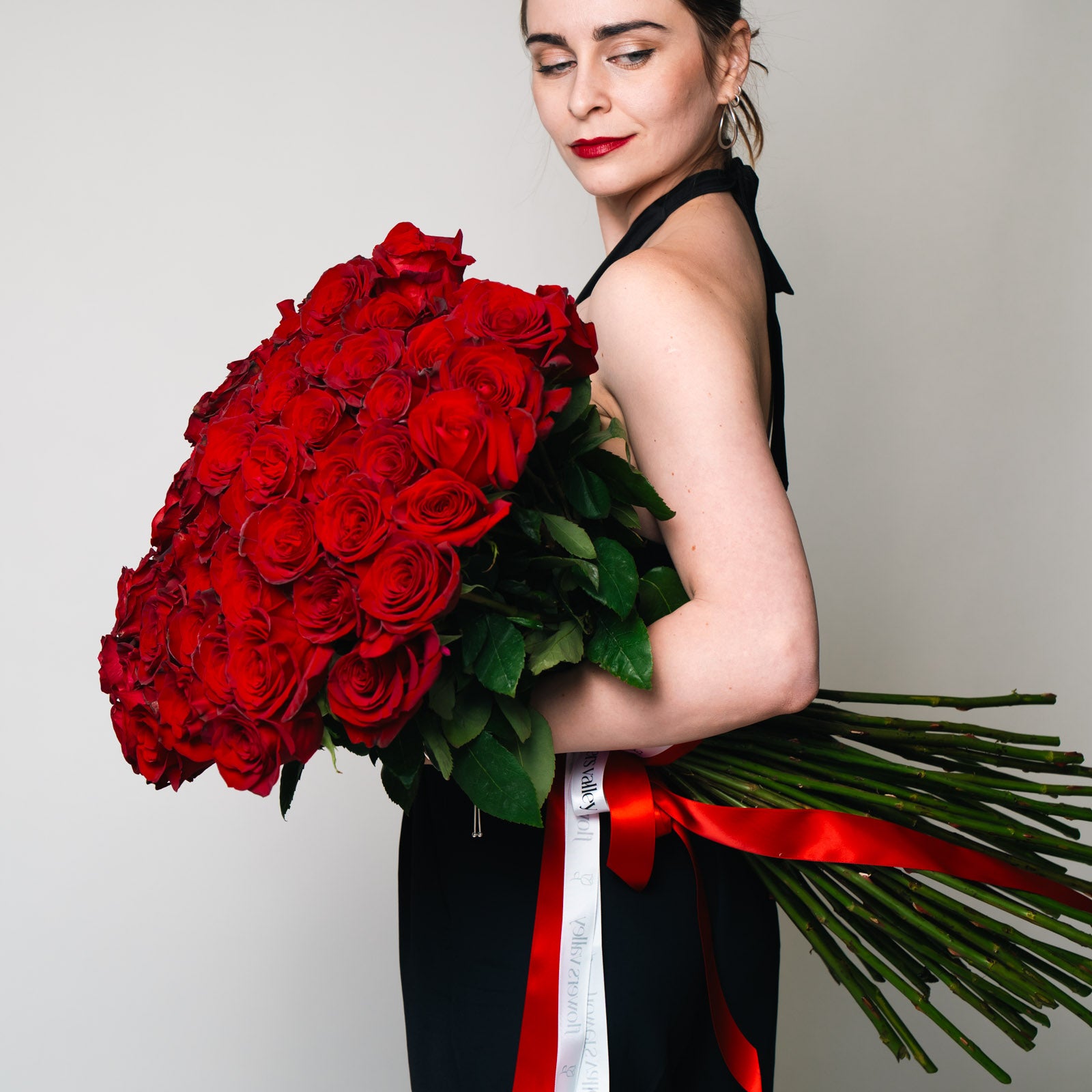 Long-stem Red Roses flower bouquet, featuring a luxurious bundle of long-stemmed red roses held by a woman, for premium Bay Area flower delivery from The Flowers Valley.